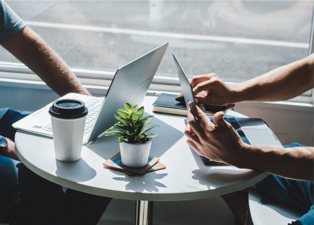 two people with laptops at a small cafe table