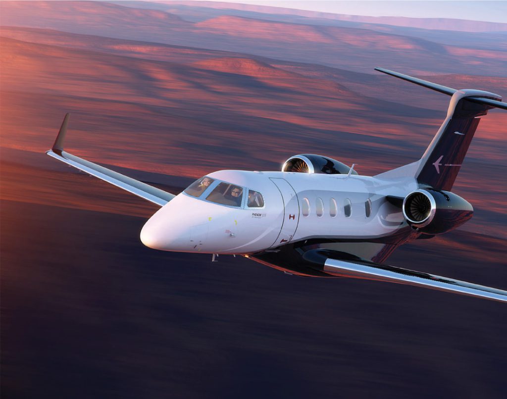 small private jet flying in the mountains at sunset